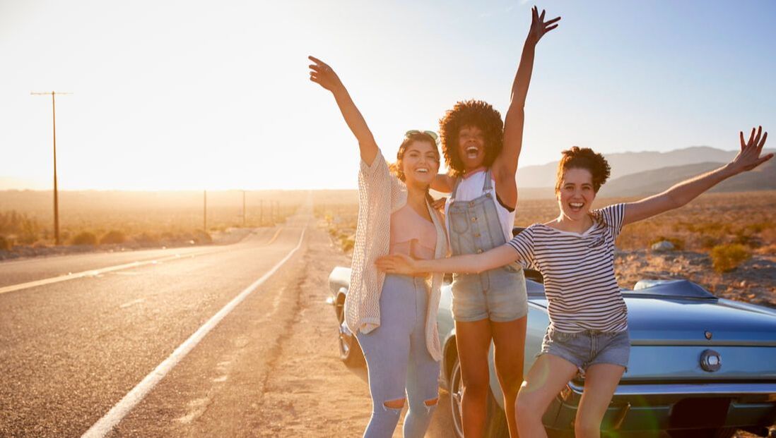 Three women on the side of the highway cheering